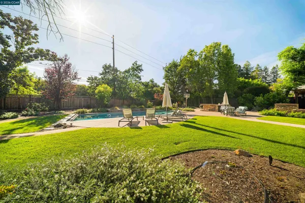 a view of swimming pool with lawn chairs and plants