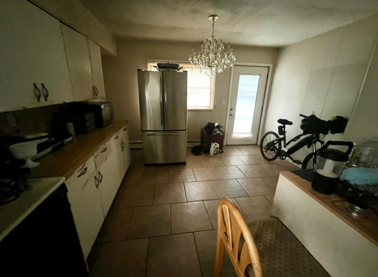 100 Maple Lane Medford, NY 11763 - Photo 6 of 13 Kitchen featuring freestanding refrigerator, white cabinets, dark tile patterned flooring, a chandelier, and stove