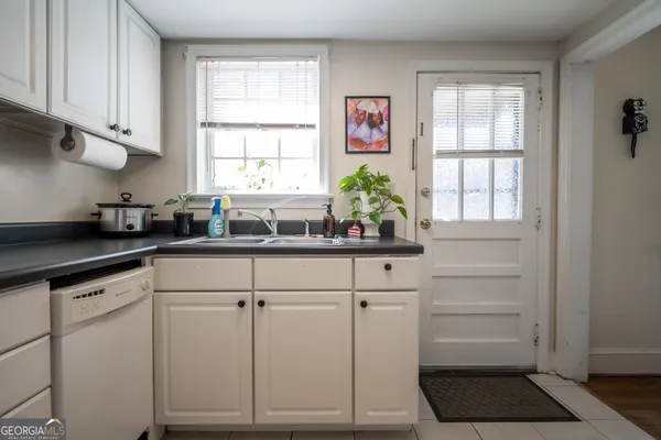 a kitchen with white cabinets and window