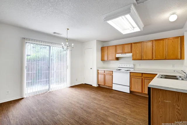 a kitchen with stainless steel appliances granite countertop wooden cabinets a stove a sink and dishwasher with wooden floor