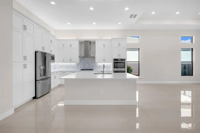 a large white kitchen with a refrigerator a stove and a sink