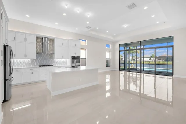 a large white kitchen with large windows and white cabinets