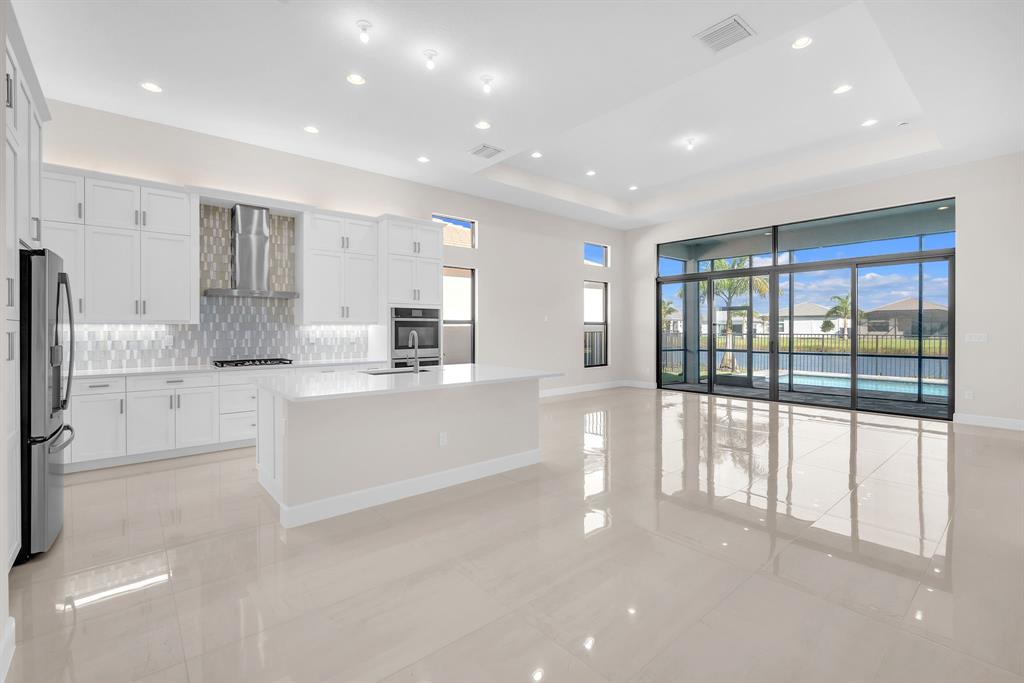10990 Violet Mdw Street Boynton Beach, FL 33473 - Photo 9 of 60 a large white kitchen with large windows and white cabinets