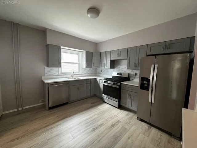 a kitchen with a refrigerator sink and wooden floor