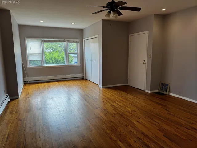 a view of empty room with wooden floor and fan