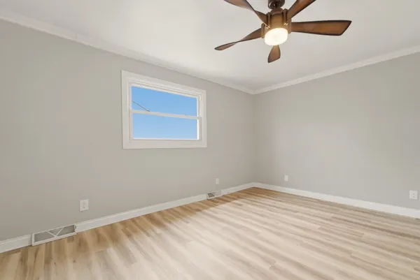 an empty room with a window and a fan