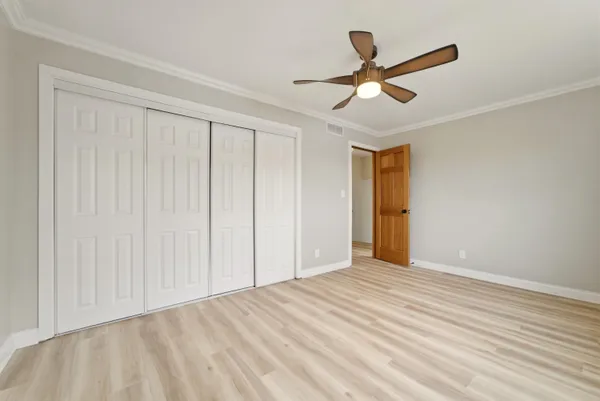 a view of empty room with wooden floor and ceiling fan