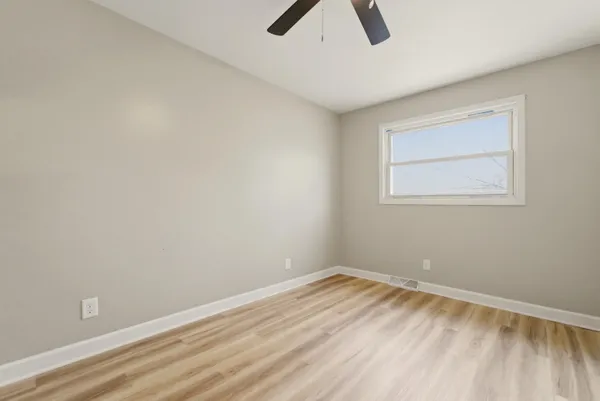 an empty room with ceiling fan and window