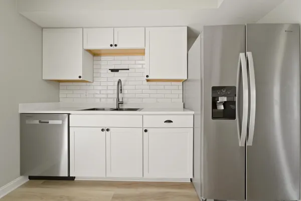 a kitchen with white cabinets and refrigerator
