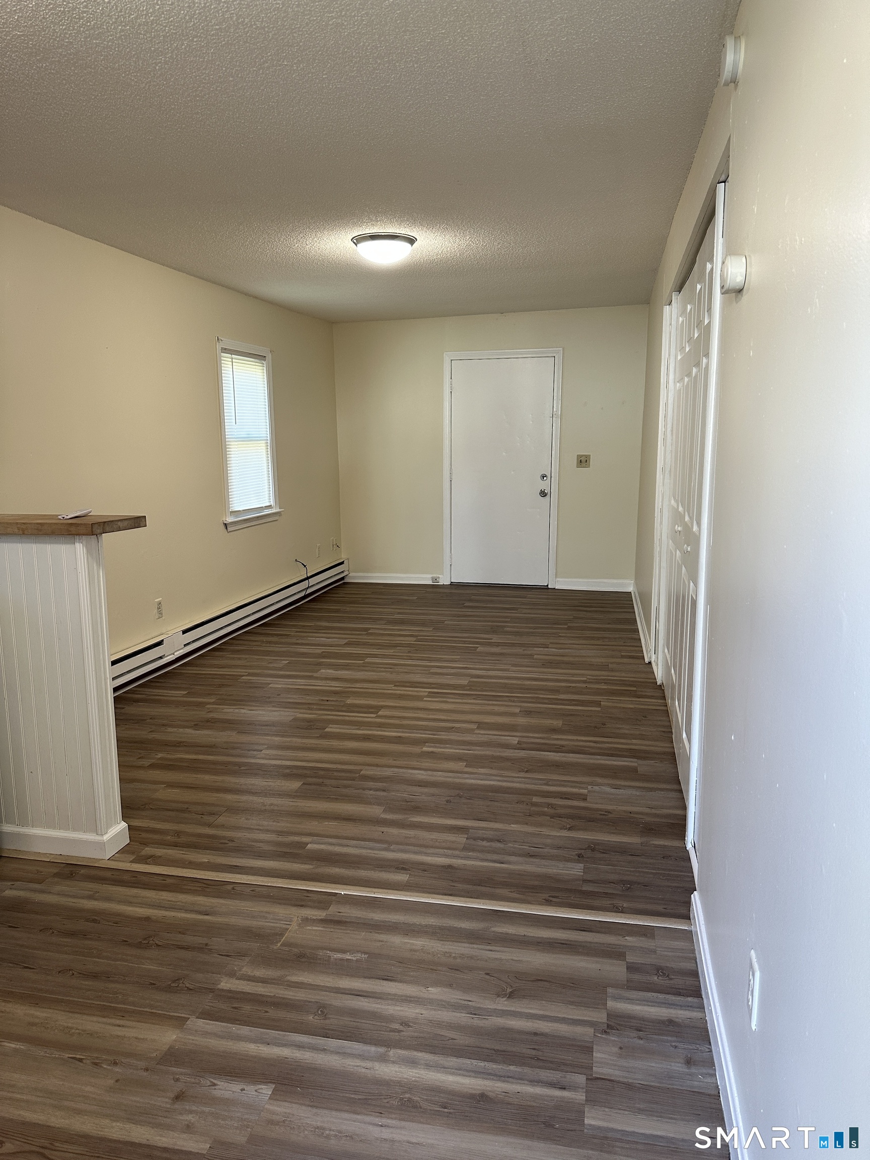 a view of an empty room with wooden floor and a window