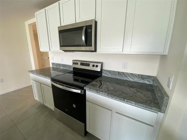 a kitchen with granite countertop a sink stove and cabinets