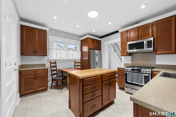 a kitchen with stainless steel appliances granite countertop a stove top oven a sink dishwasher a refrigerator and a microwave oven with large the stove