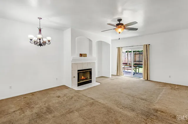 a view of a livingroom with a ceiling fan a fireplace and a chandelier