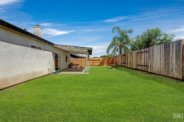 a view of a backyard with wooden fence and a bench