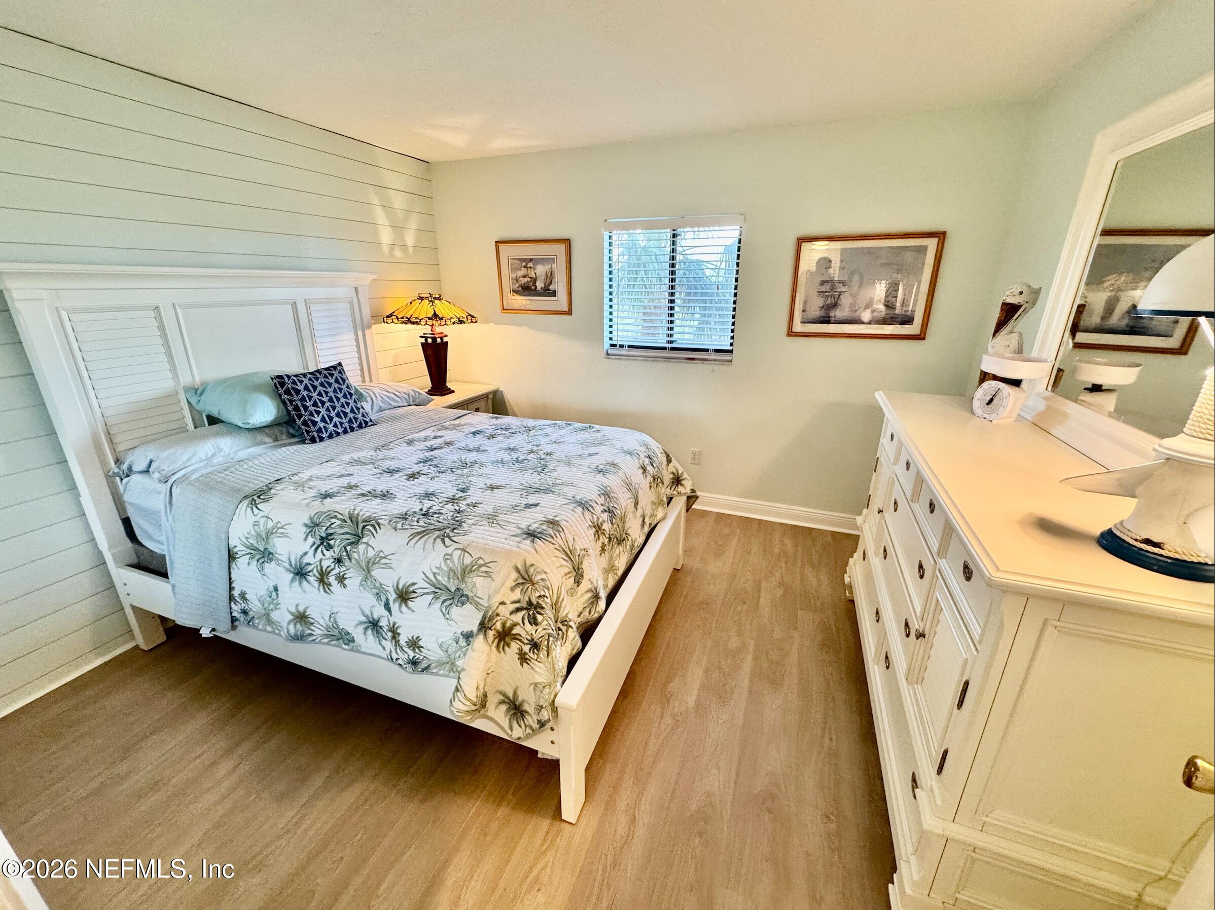 8711 Blind Pass Road, Unit 208A St. Petersburg, FL 33706 - Photo 2 of 21 a bedroom with a bed and wooden floor