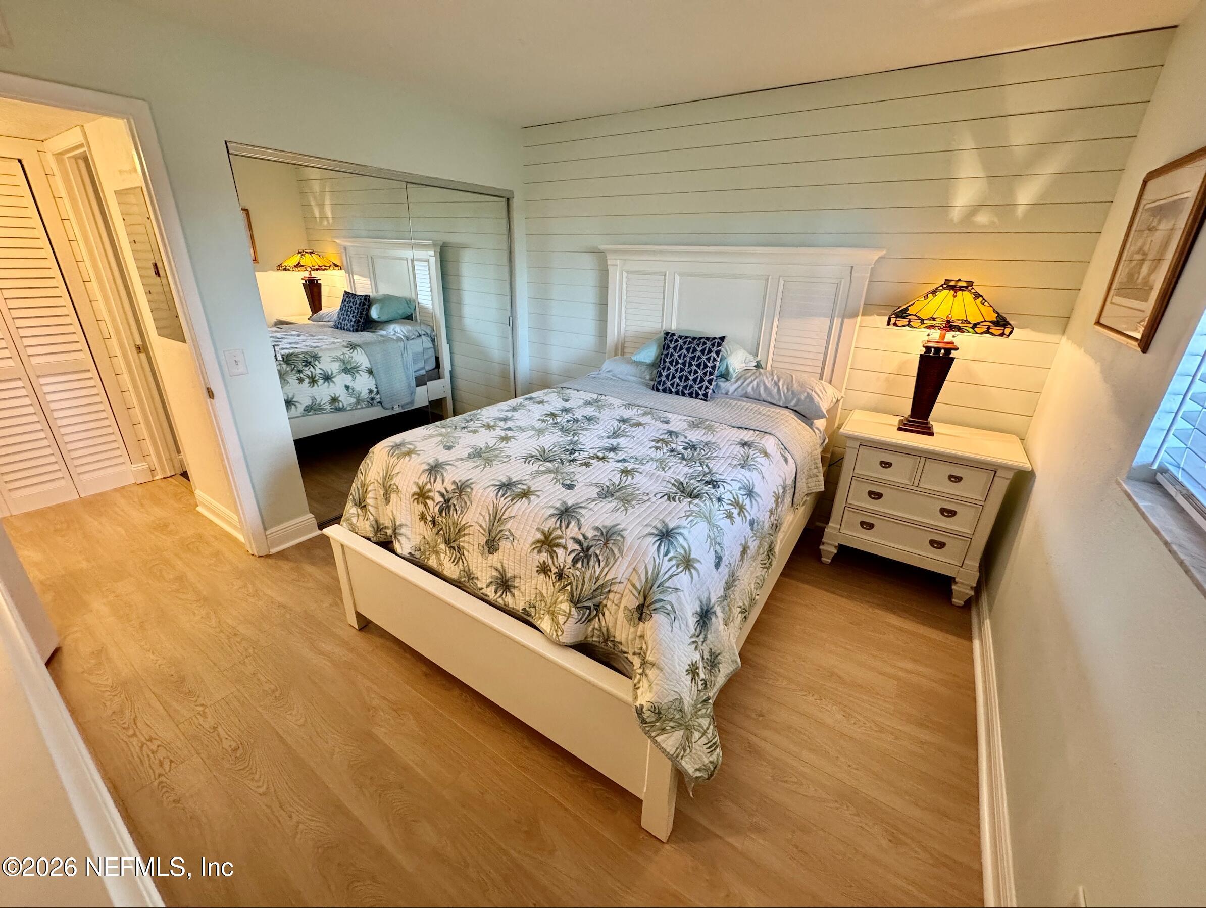 8711 Blind Pass Road, Unit 208A St. Petersburg, FL 33706 - Photo 3 of 21 a bedroom with a bed and wooden floor