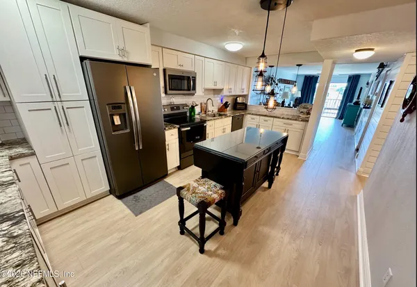 a living room with stainless steel appliances furniture a rug a kitchen island a rug wooden floor and a view of kitchen