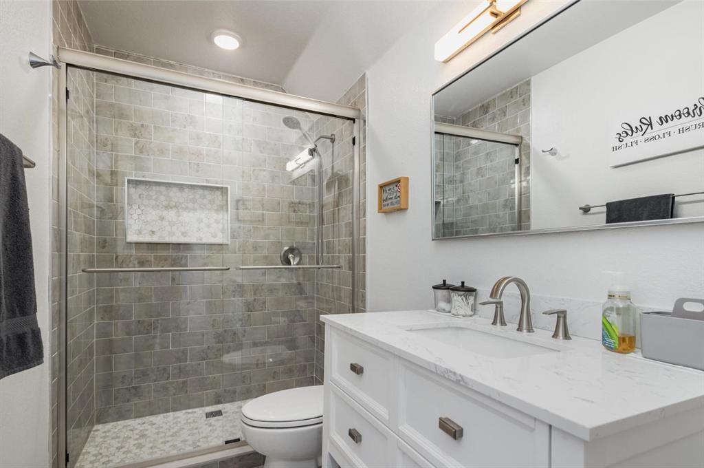 601 Gin Road Ennis, TX 75119 - Photo 21 of 33 a bathroom with a sink toilet a mirror and shower