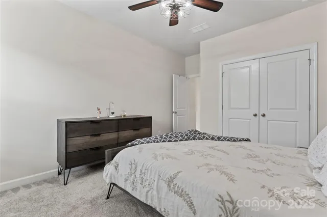 a bedroom with a bed and a chandelier fan
