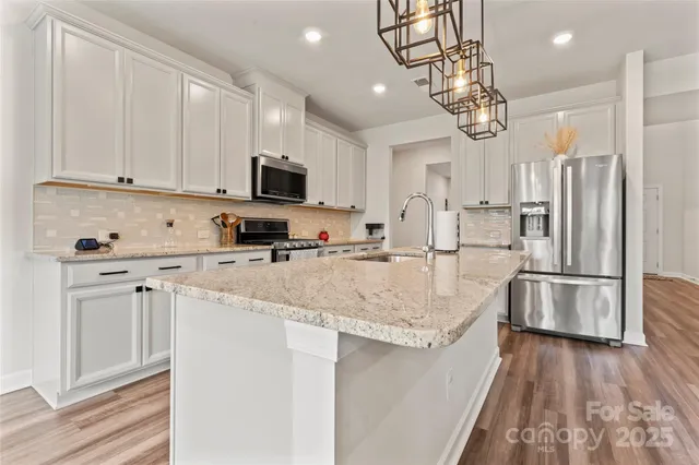 a kitchen with stainless steel appliances granite countertop a sink refrigerator and cabinets