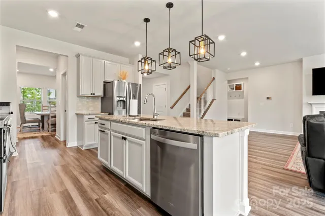 a kitchen with stainless steel appliances granite countertop a stove a sink and a wooden floor