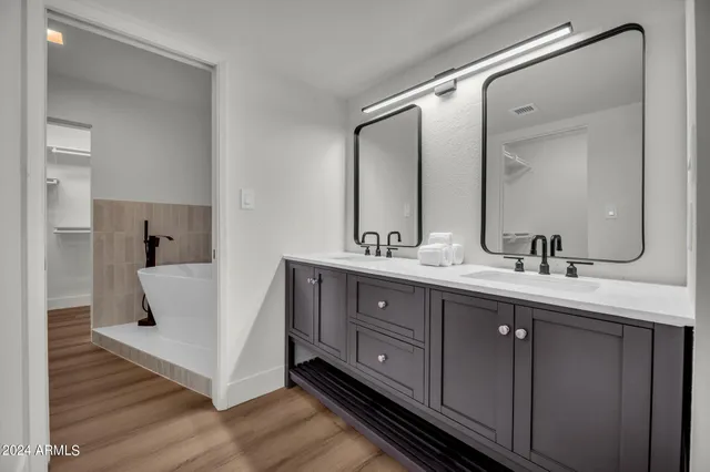a bathroom with a double vanity sink mirror and bathtub