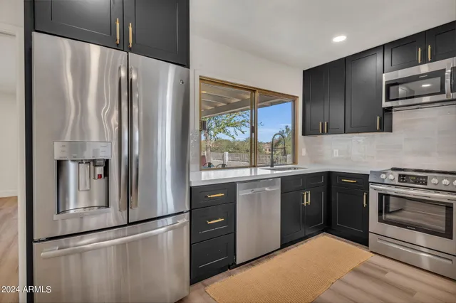 a kitchen with stainless steel appliances granite countertop a refrigerator a sink and a stove