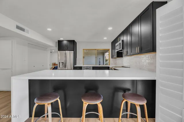 a kitchen with white cabinets and chairs