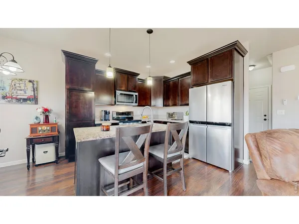 a kitchen with stainless steel appliances kitchen island granite countertop a sink a stove a refrigerator a dining table and chairs