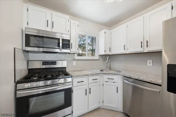 a kitchen with granite countertop white cabinets and stainless steel appliances
