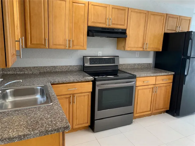 a kitchen with granite countertop a sink stove and refrigerator