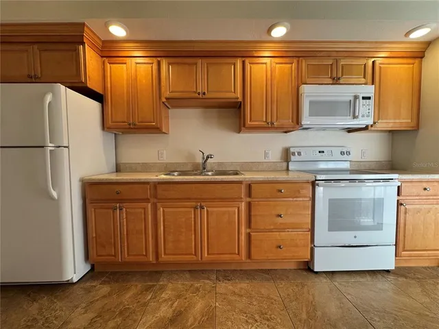 a kitchen with stainless steel appliances granite countertop a refrigerator sink and stove