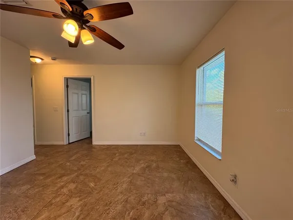 an empty room with a window and a fan