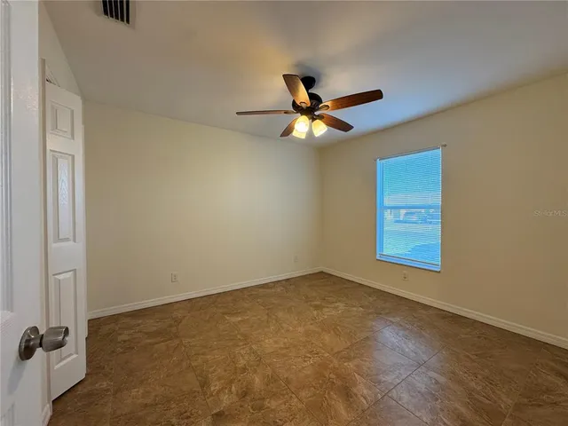 an empty room with a window and a fan