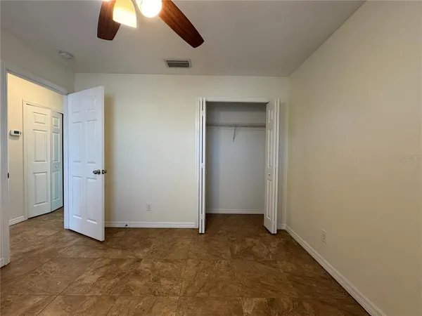 an empty room with closet and chandelier fan