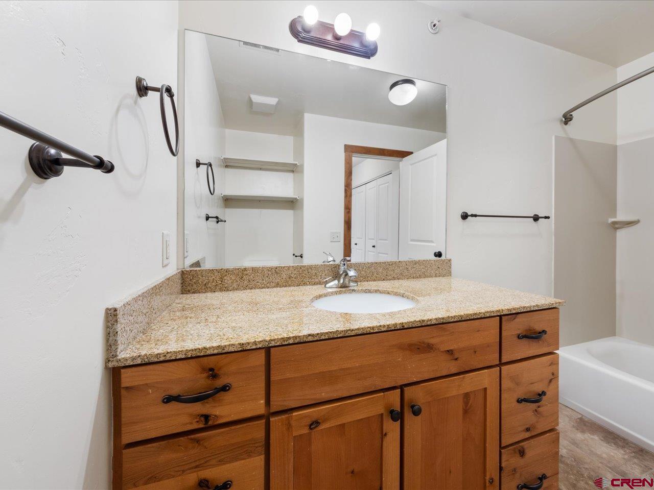550 Redcliff Circle, Unit D202 Ridgway, CO 81432 - Photo 22 of 29 a bathroom with a granite countertop sink and a mirror