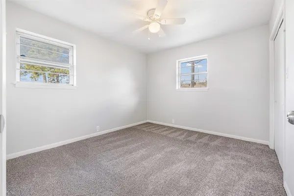 an empty room with a window and a fan