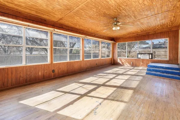 a view of an empty room with a window and wooden floor