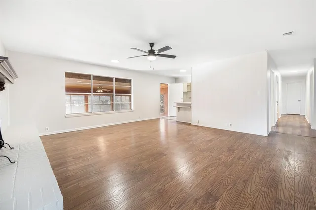 a view of an empty room with window and wooden floor