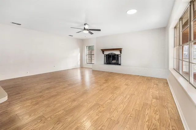 an empty room with wooden floor fan and windows