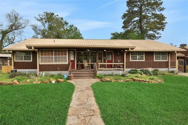 a front view of a house with a garden and trees
