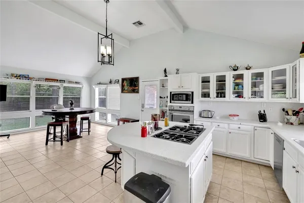 a kitchen with a stove a sink a dining table and chairs