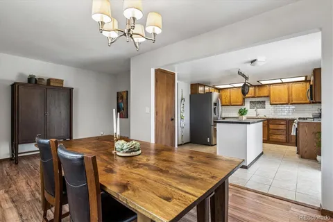 a kitchen with stainless steel appliances kitchen island granite countertop a table chairs in it and wooden floors