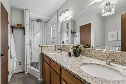 a bathroom with a granite countertop sink a mirror and shower