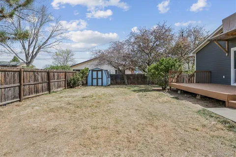a backyard of a house with large trees and outdoor seating