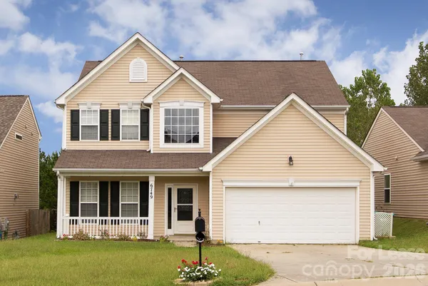 a view of a white house with a small yard and plants