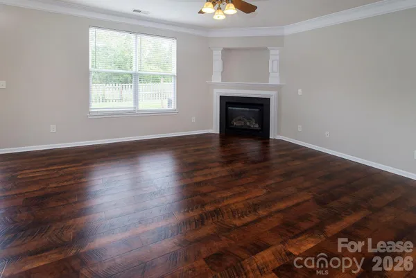 an empty room with wooden floor fireplace and windows