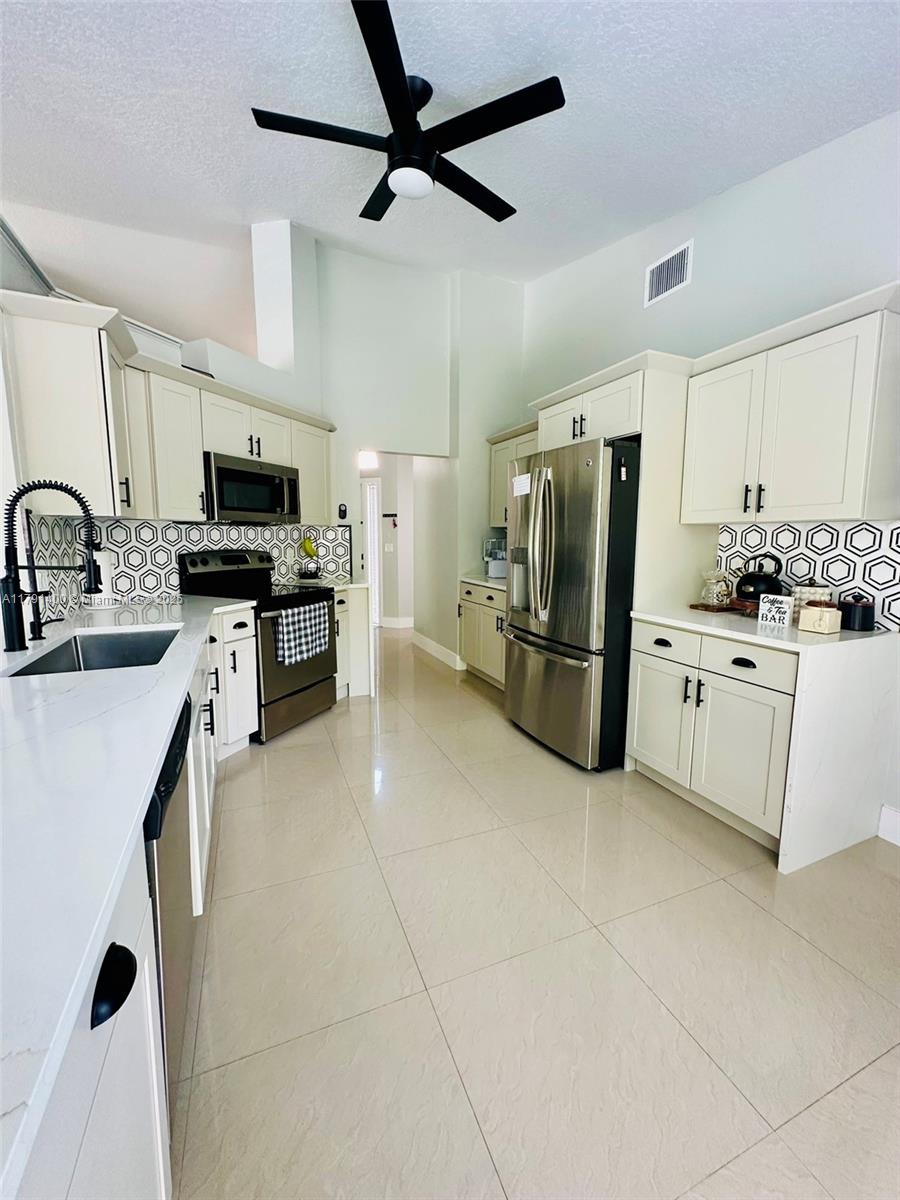 3961 Antigua Point Drive Boca Raton, FL 33487 - Photo 17 of 65 a kitchen with stainless steel appliances a refrigerator sink and microwave