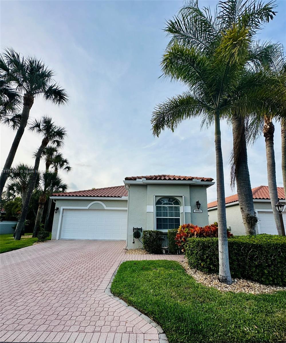 3961 Antigua Point Drive Boca Raton, FL 33487 - Photo 44 of 65 a front view of a house with a garden and trees