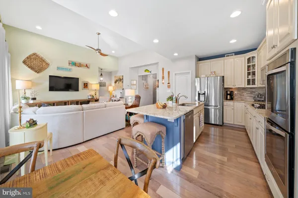 a kitchen with stainless steel appliances granite countertop a dining table chairs refrigerator microwave and cabinets